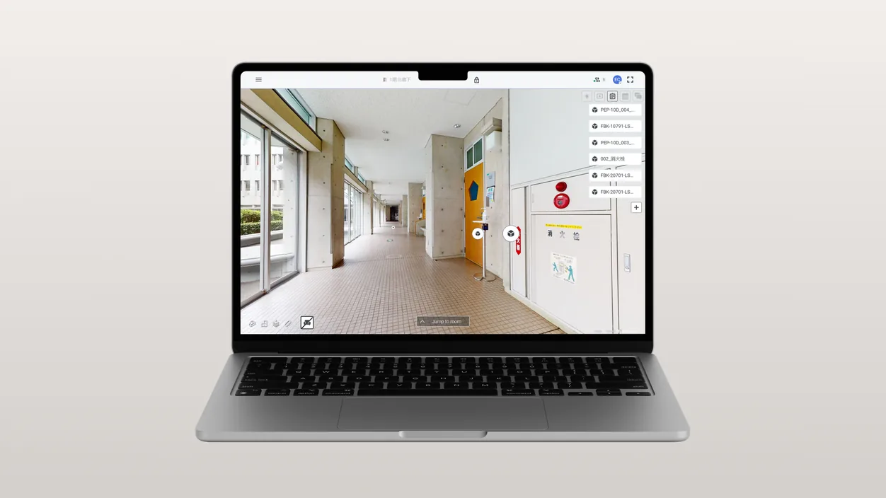 A laptop showing SIM-ON with a 3D walkthrough of a Toyo University corridor, fire equipment tagged on the wall and a list of tagged assets beside it.